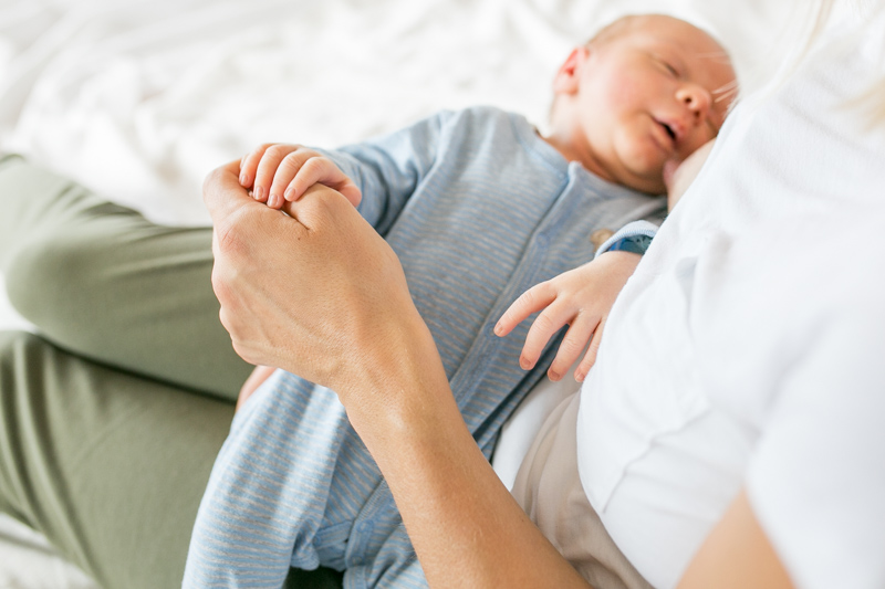 Neugeborenes Baby auf dem Arm der Mama beim Stillen